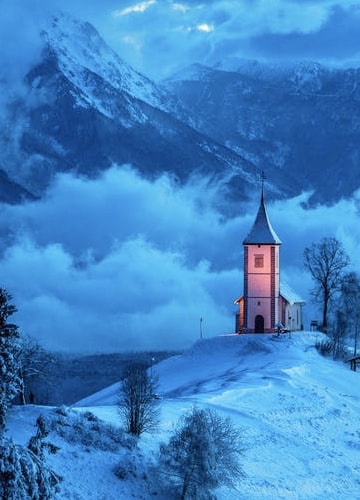 picture of a small church among cloudy and snowy mountains